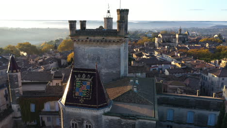 Duchy-of-Uzès-or-Duke's-castle-aerial-view-during-sunrise-France-Gard-emblem